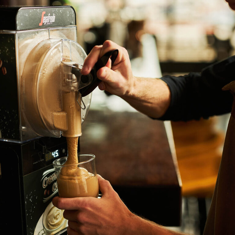 Close-Up-Imagebild Hand füllt Crema Caffè in ein Glas
